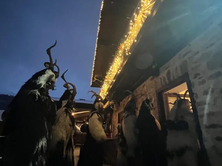 Maskovaná postava Krampuse osvětlená pochodněmi při tradičním adventním krampusovém průvodu v Gasteinu.