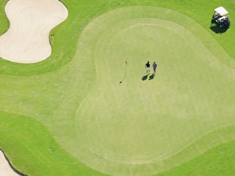 Zelená fairway gasteinského golfového hřiště rozloženého pod horami.