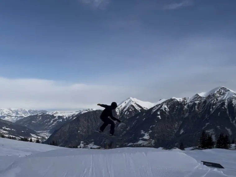 Snowboardista jedoucí čerstvým sněhem na gasteinském svahu.