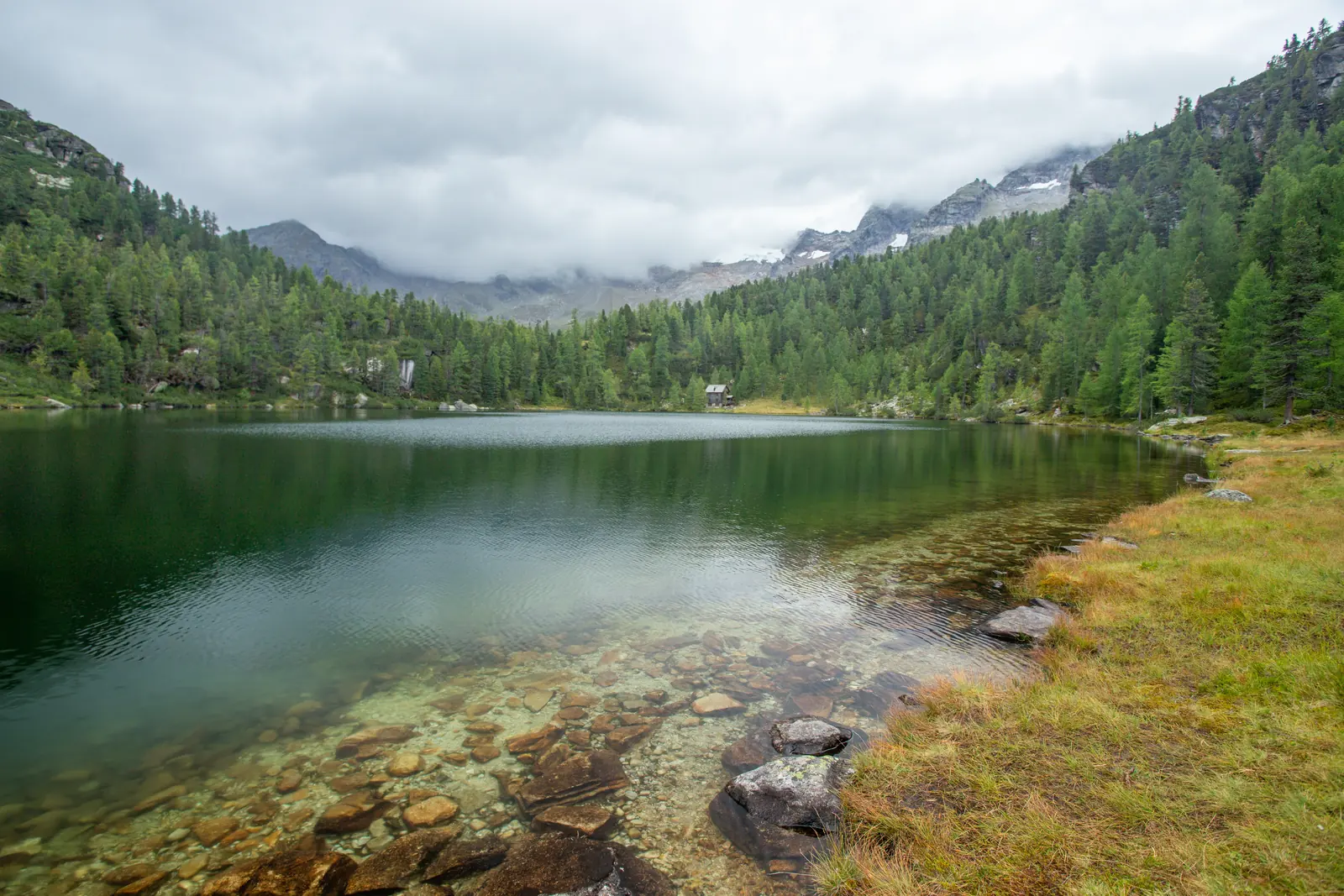 Klidné horské jezero zrcadlící zalesněné svahy Vysokých Taur nad údolím Kötschachtal.