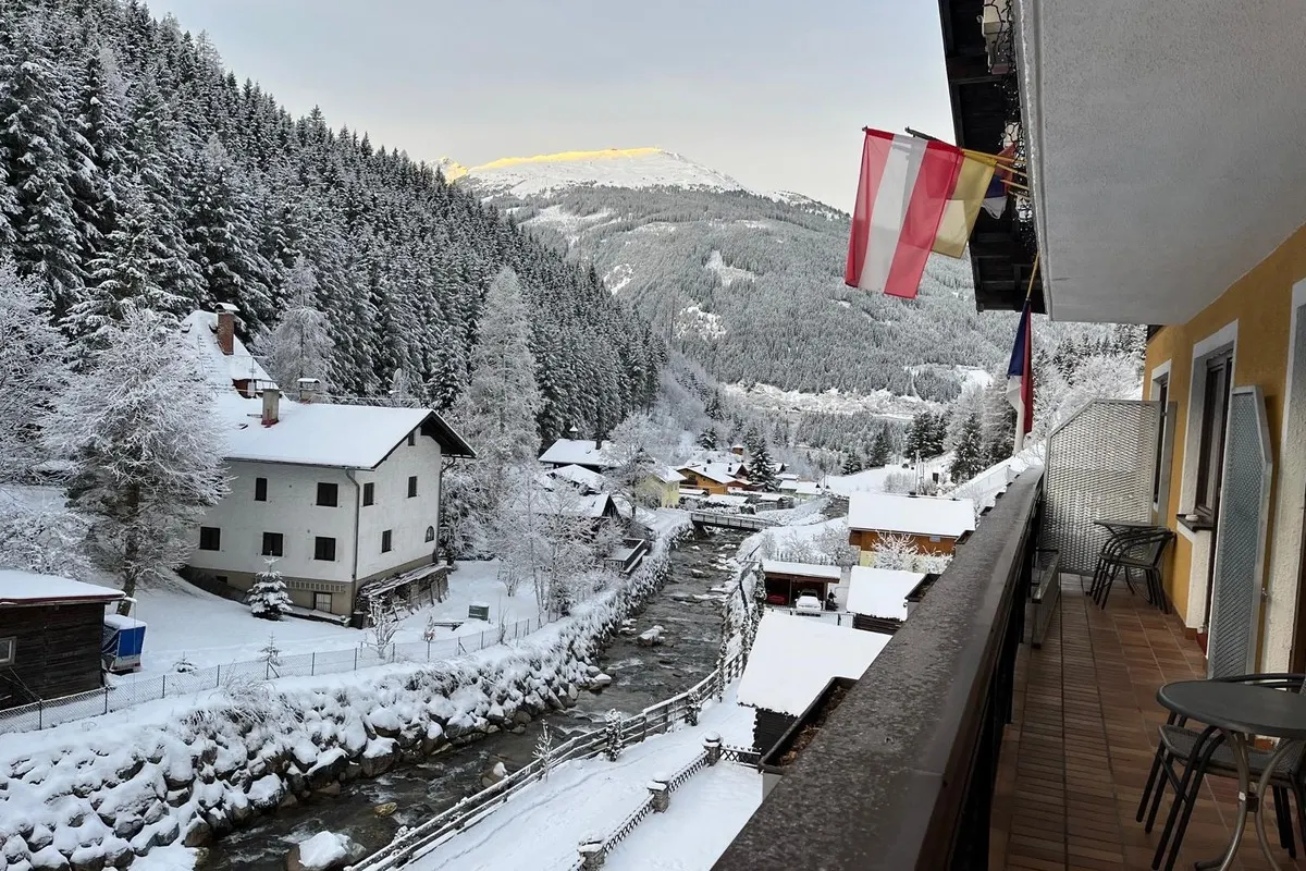 Zasněžené údolí Kötschachtal z balkonu Stubnerhofu, s prvním sluncem na hřebeni.